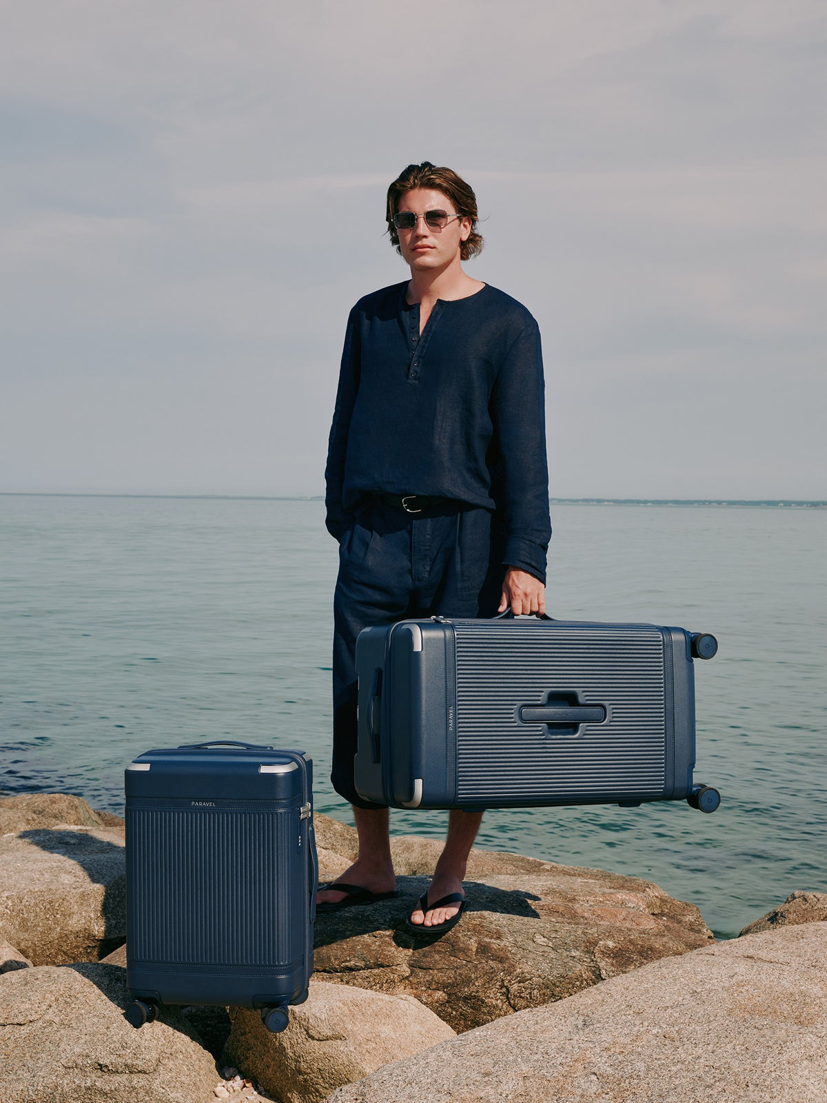 a man holding luggage on a rock