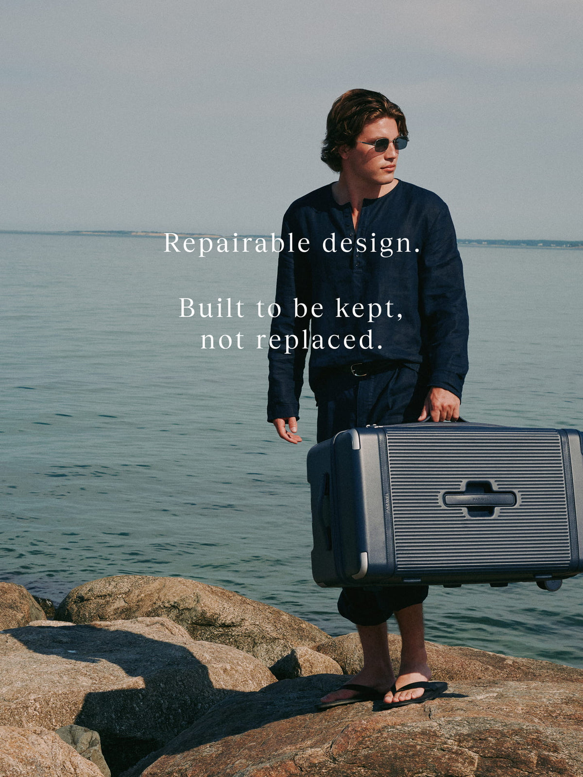 a man holding a suitcase on a rocky beach