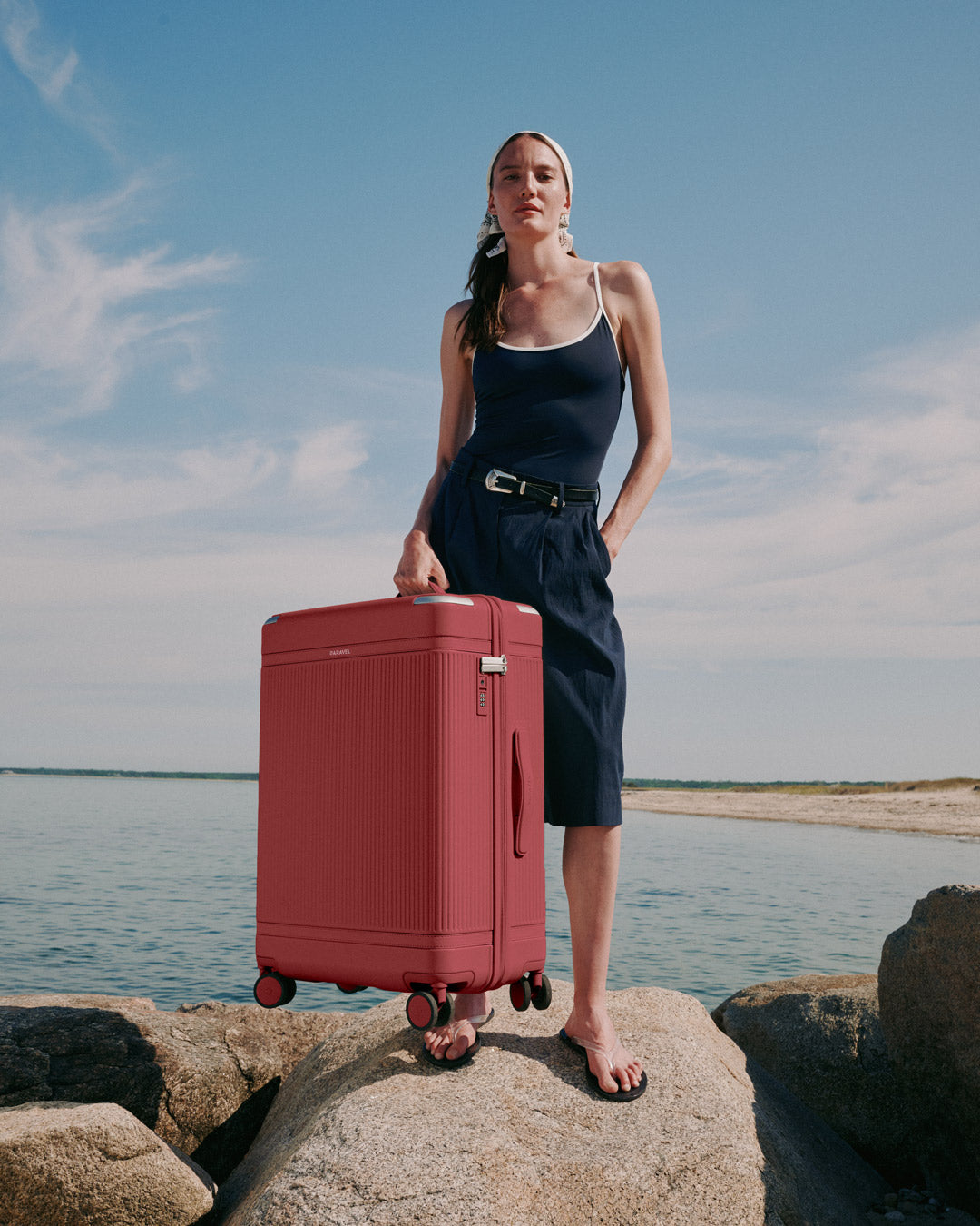 a woman standing on a rock with a suitcase