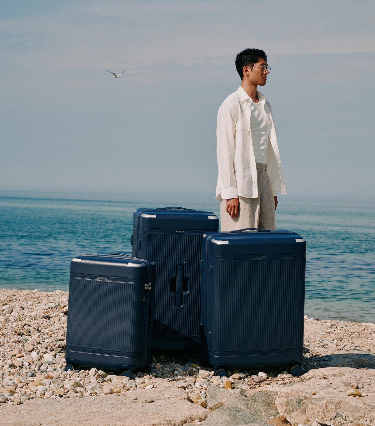 a man standing next to a group of luggage on a beach