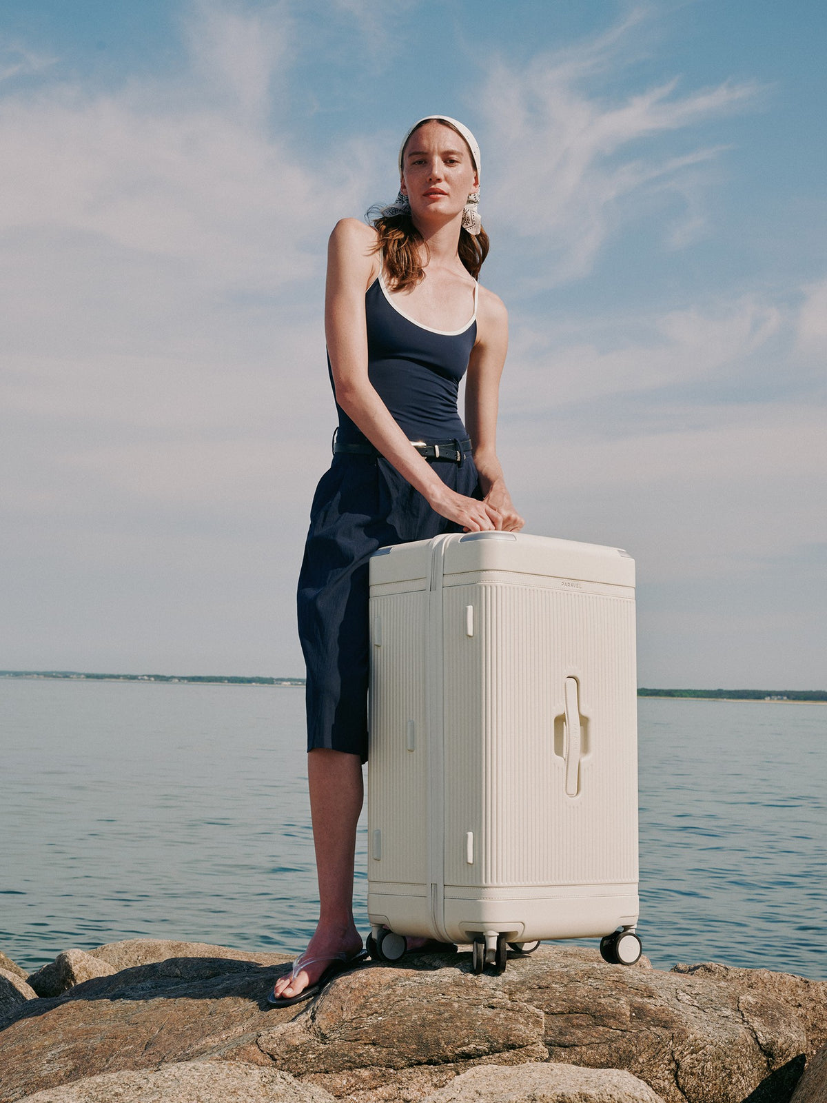 a woman standing on a large white suitcase