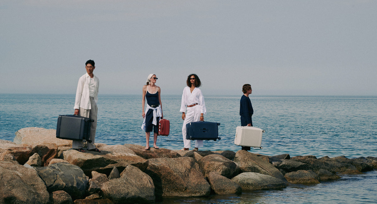 a group of people standing on rocks with luggage
