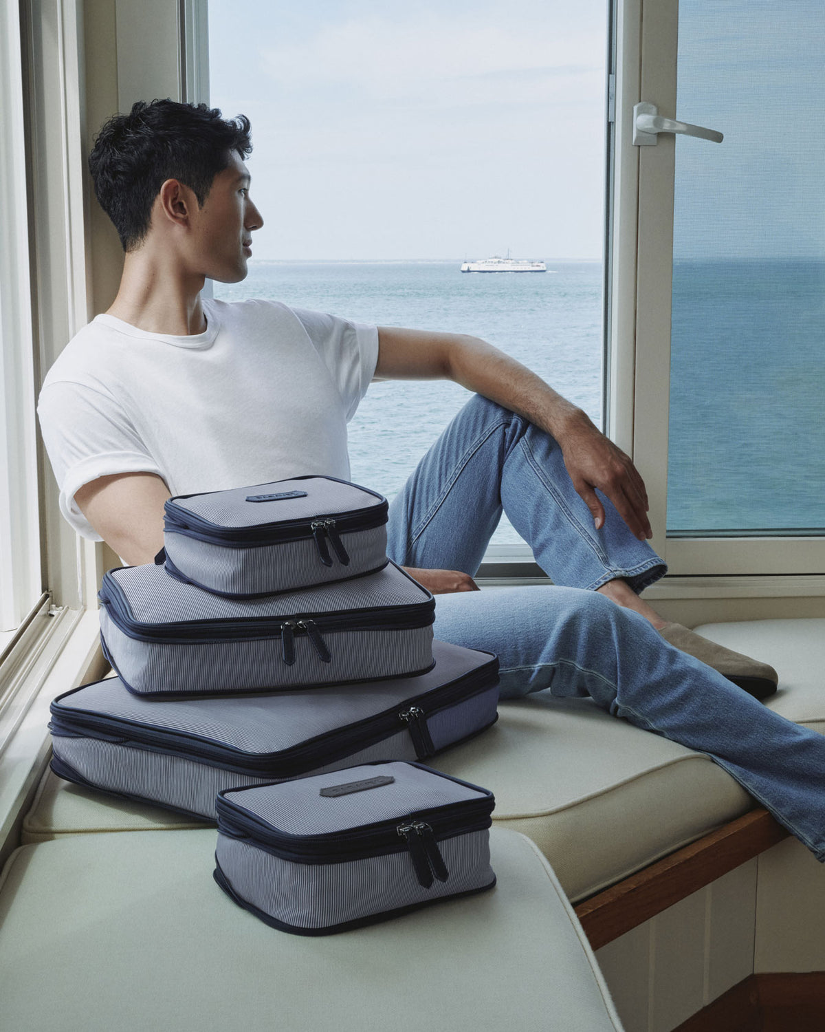 a man sitting on a window sill with luggage