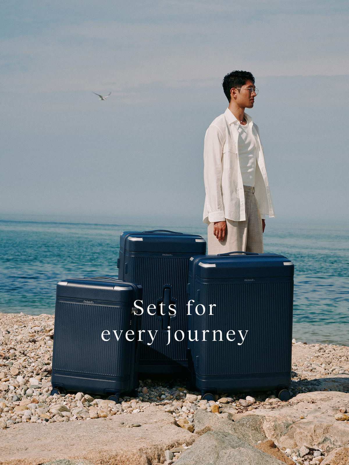 a man standing next to a group of luggage on a beach